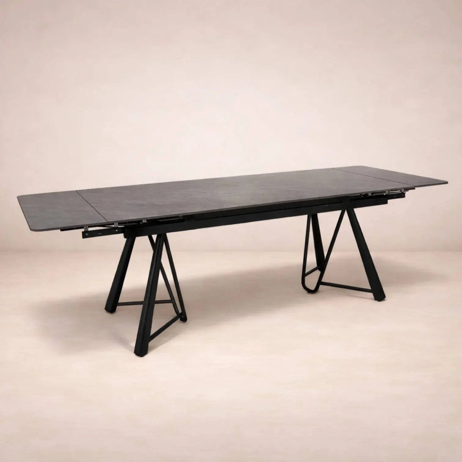 Mesa de comedor extensible de color gris oscuro con superficie de cerámica y base metálica, vista frontal.