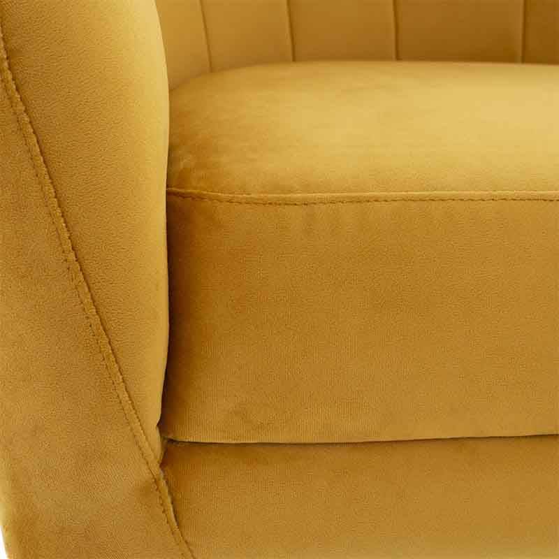 Sillón ocasional Andor de tapiz amarillo de terciopelo, con respaldo y asiento acolchados, en un espacio moderno.