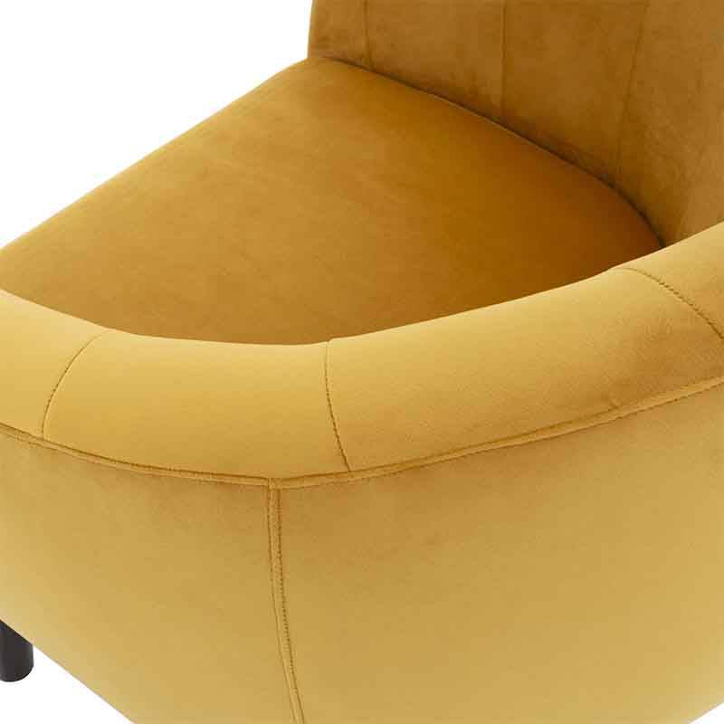 Sillón ocasional Andor de tapiz amarillo de terciopelo, con respaldo y asiento acolchados, en un espacio moderno.